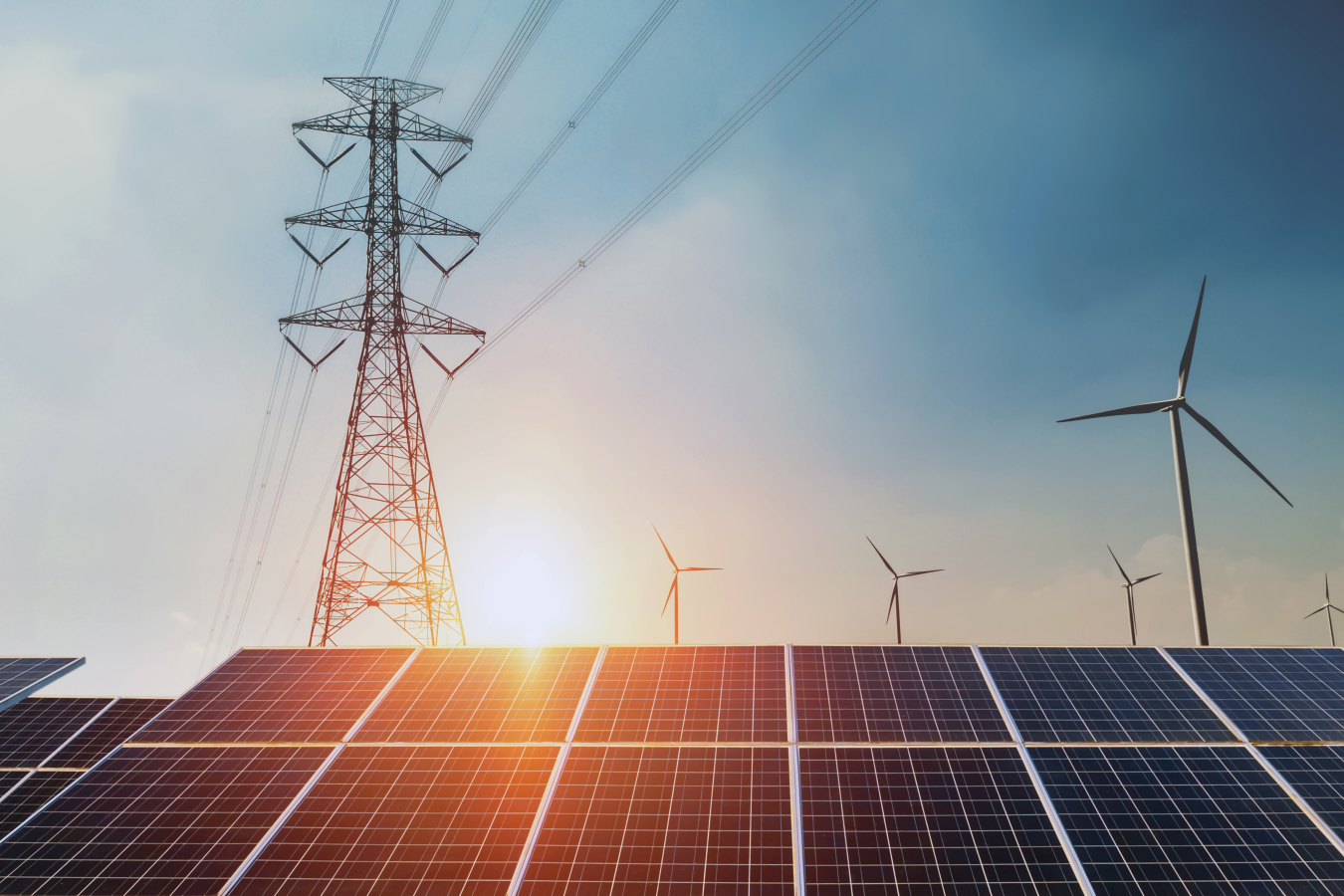 Solar panels and wind turbines surround a transmission tower.