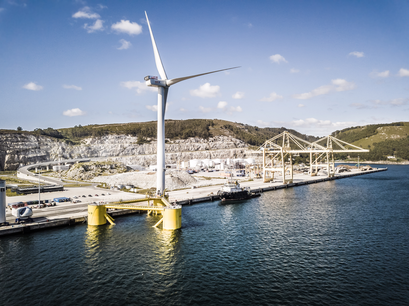 A wind turbine floating just off a dock.