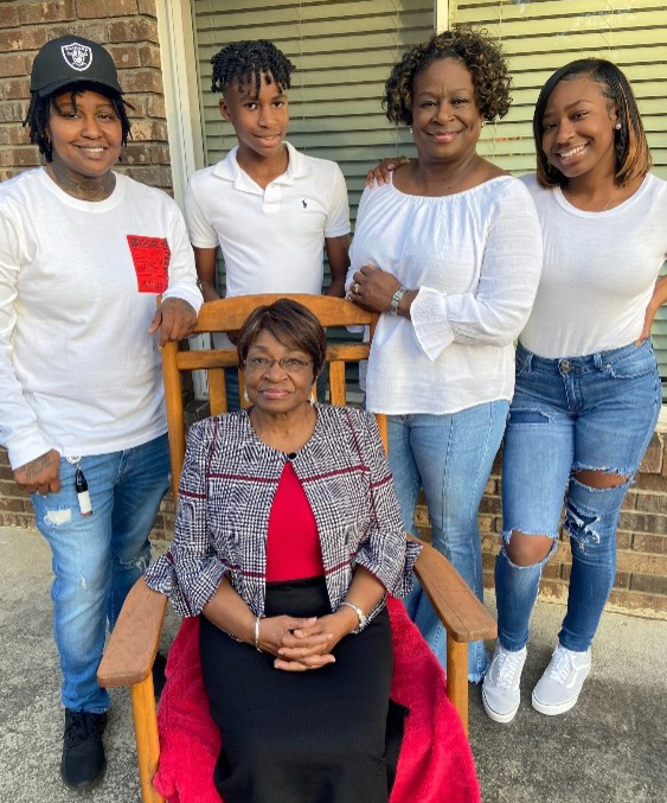 Tina Whitt's mother sits in a chair. Tina Whitt, her two children, and one grandson all stand behind her.