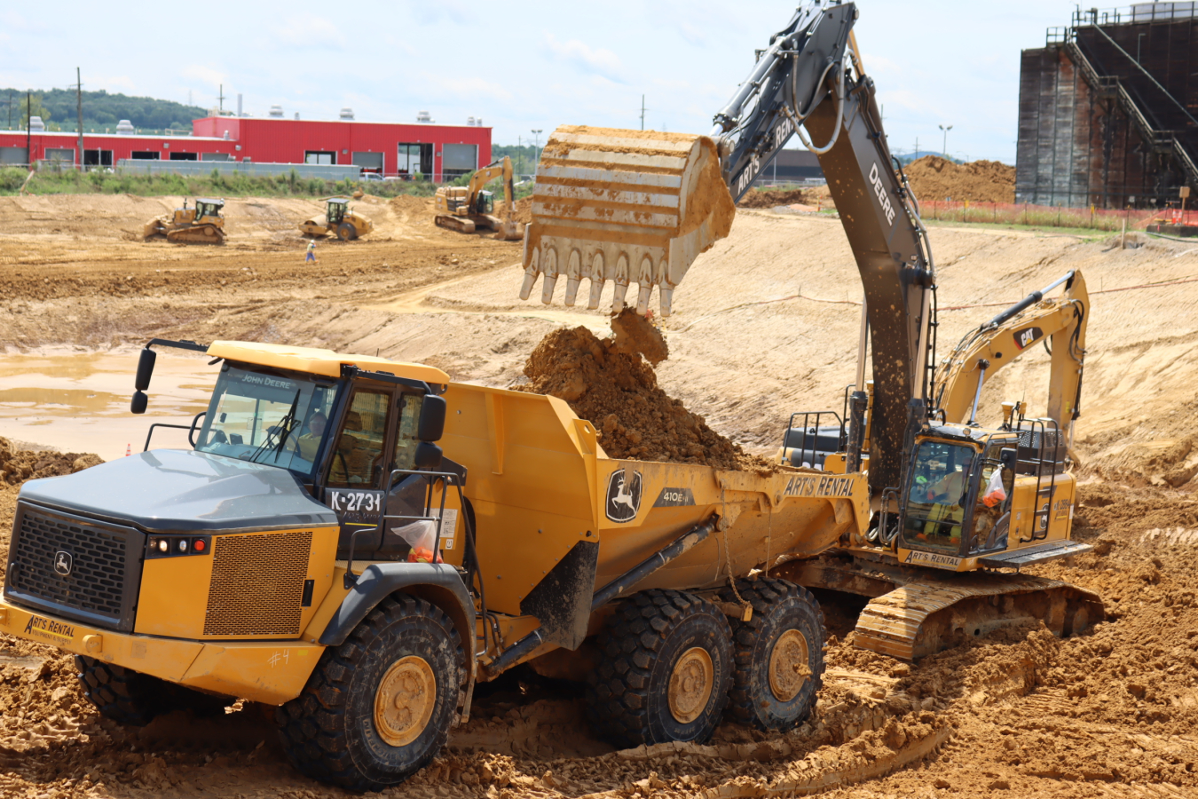 A heavy equipment operator loads soil into a dump truck for transport to the On-Site Waste Disposal Facility.