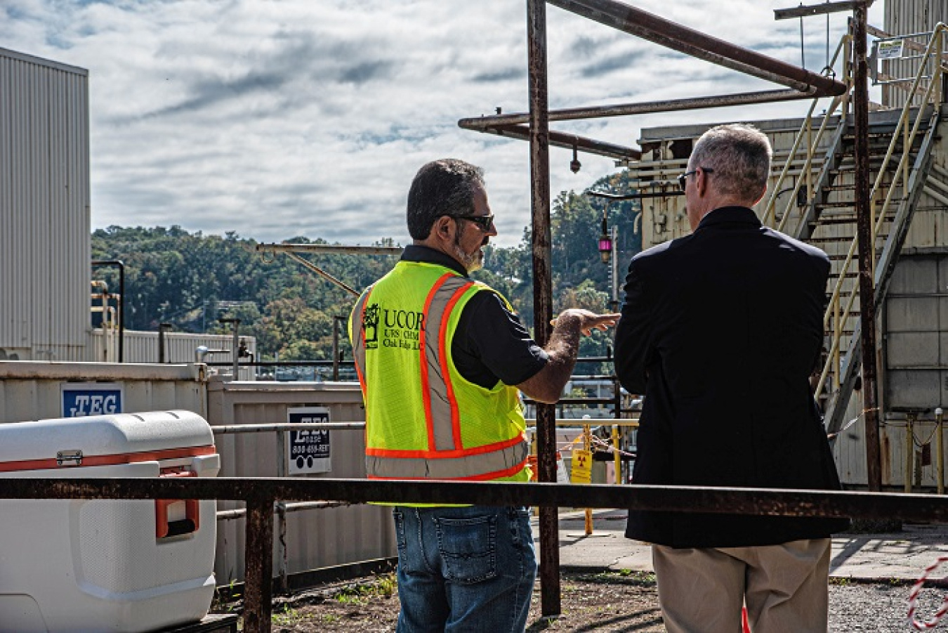 UCOR Cleanup Manager Dan Macias, left, and EM Senior Advisor William “Ike” White discuss cleanup progress underway in Oak Ridge National Laboratory’s central campus. The Low Intensity Test Reactor, pictured, is the next building slated for demolition in the central campus area.