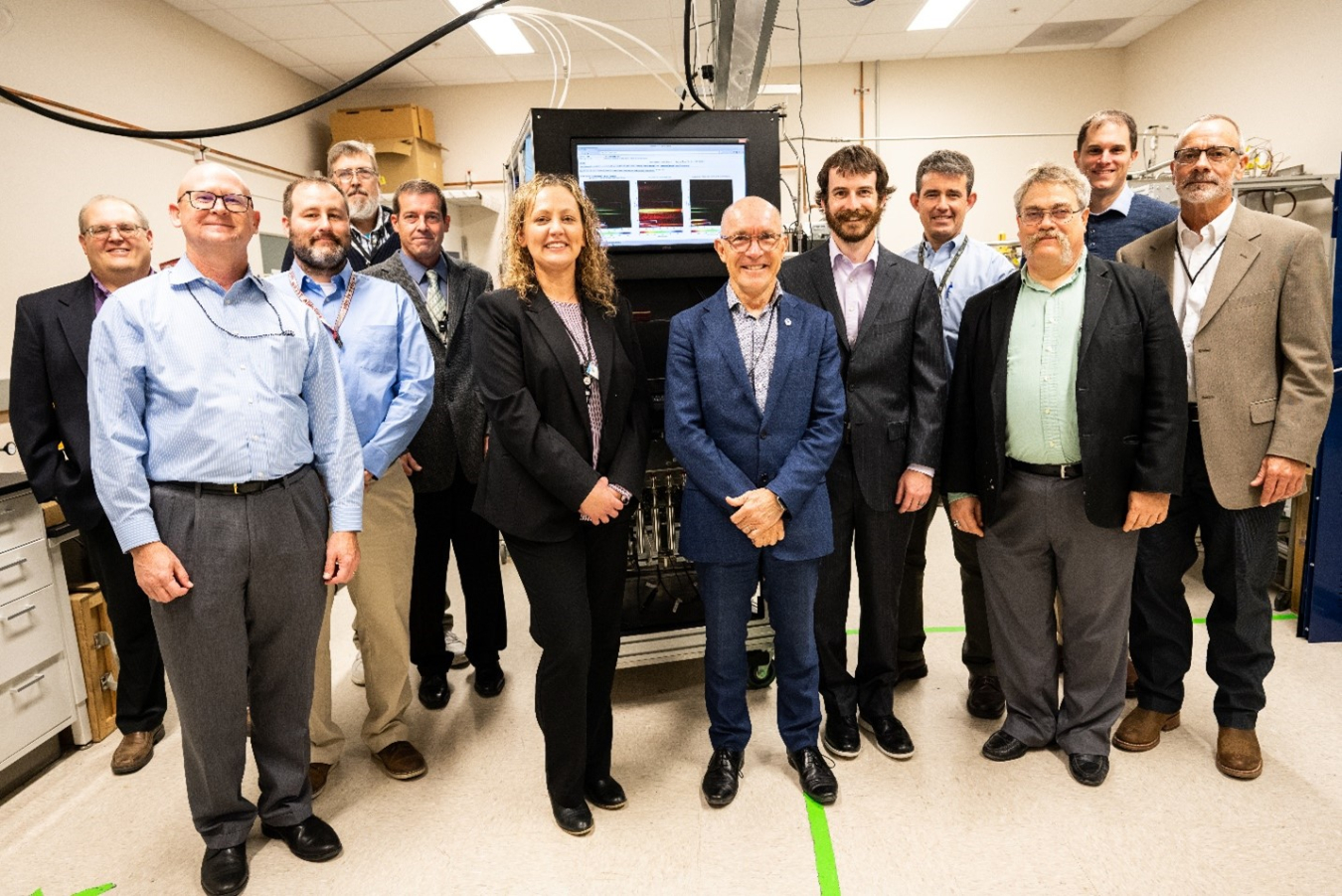 PNNL staff involved in research for radioxenon detection pose with Robert Floyd along with visitors from the Departments of Defense and State and NNSA with the Xenon International noble gas collection and analysis system.