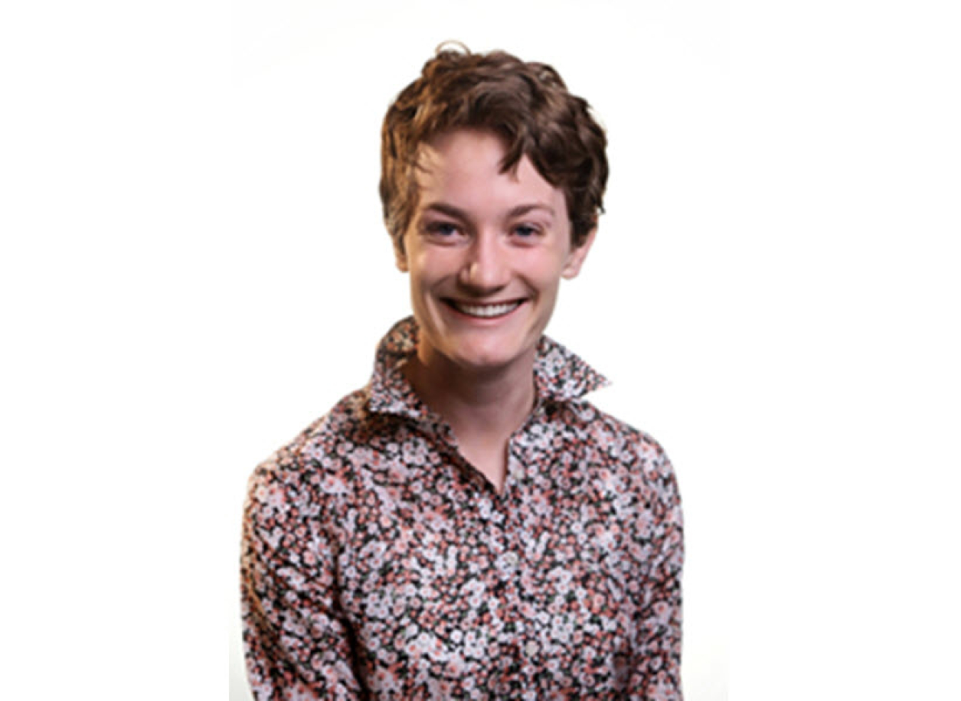 Headshot of a young woman with a white background. She has short hair, is wearing a floral button-up top, and is smiling warmly.