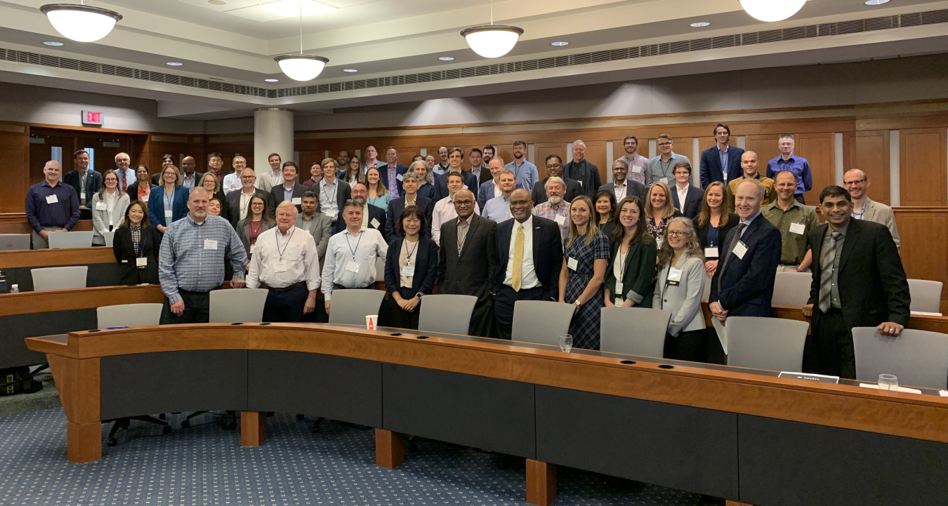 Group of people standing facing the camera inside a conference room.