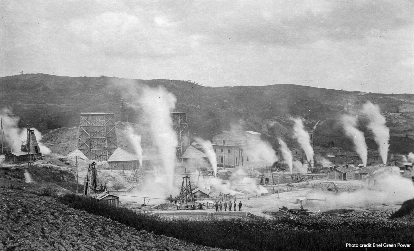 A black and white photo shows a geothermal power plant in 1904 with steam rising.