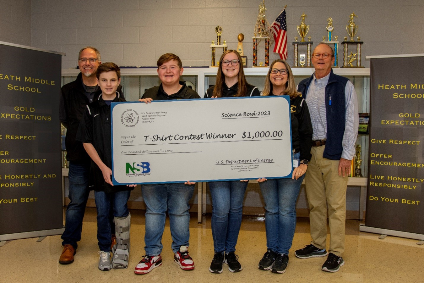 Students pose with a $1,000 check awarded to HMS for the students’ winning design for the 2023 DOE West Kentucky Regional Science Bowl t-shirt contest.