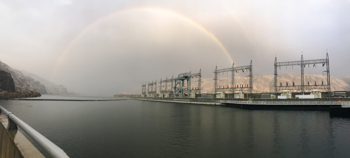 A rainbow arcing over a hydropower facility