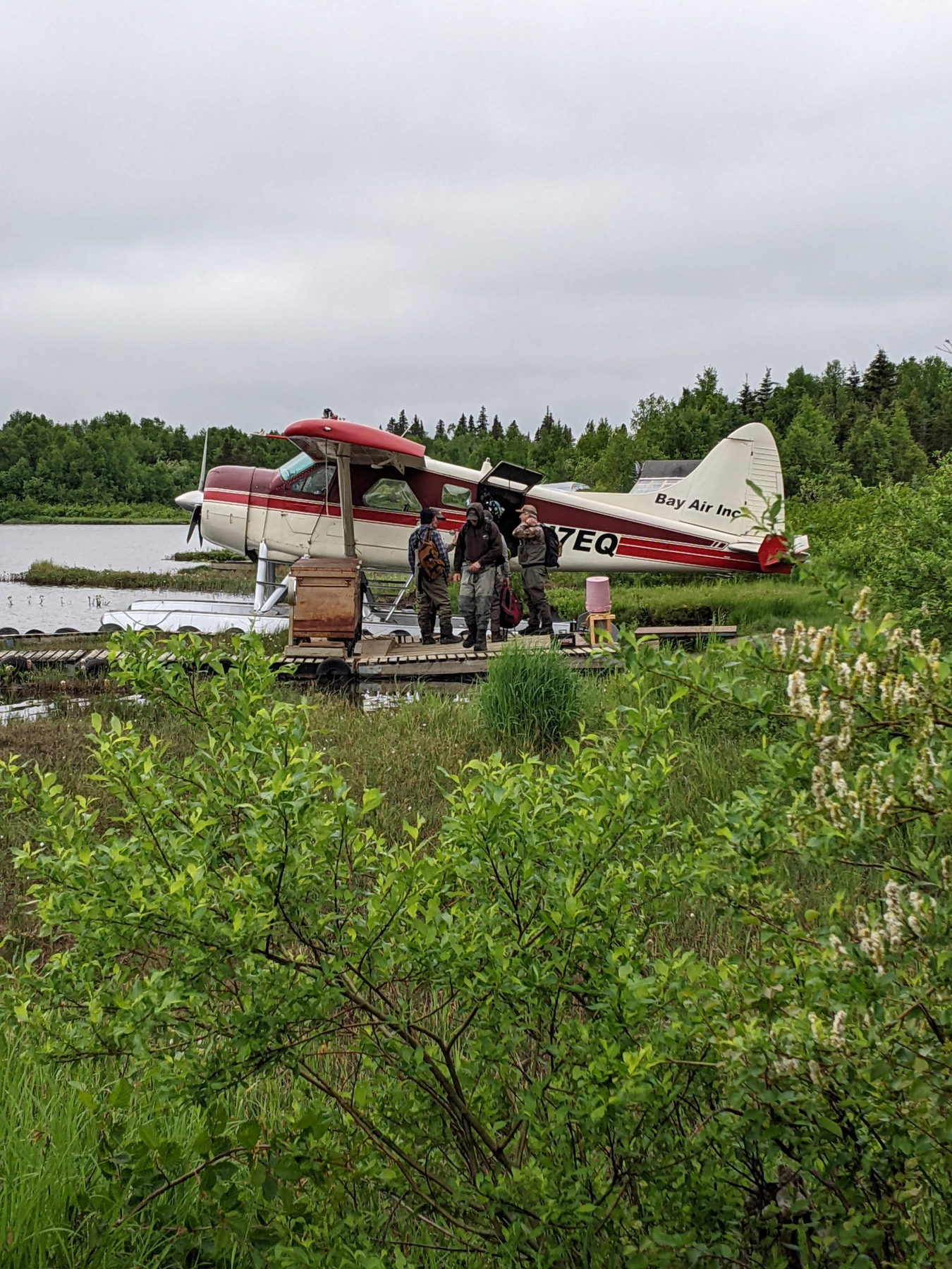 Personas junto a un avión de agua en la orilla de un río