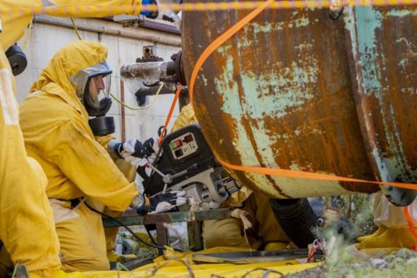 Mechanics use a magnetic drill to cut a sample from cylinders used in the feed process at the C-333-A Feed Vaporization Facility.