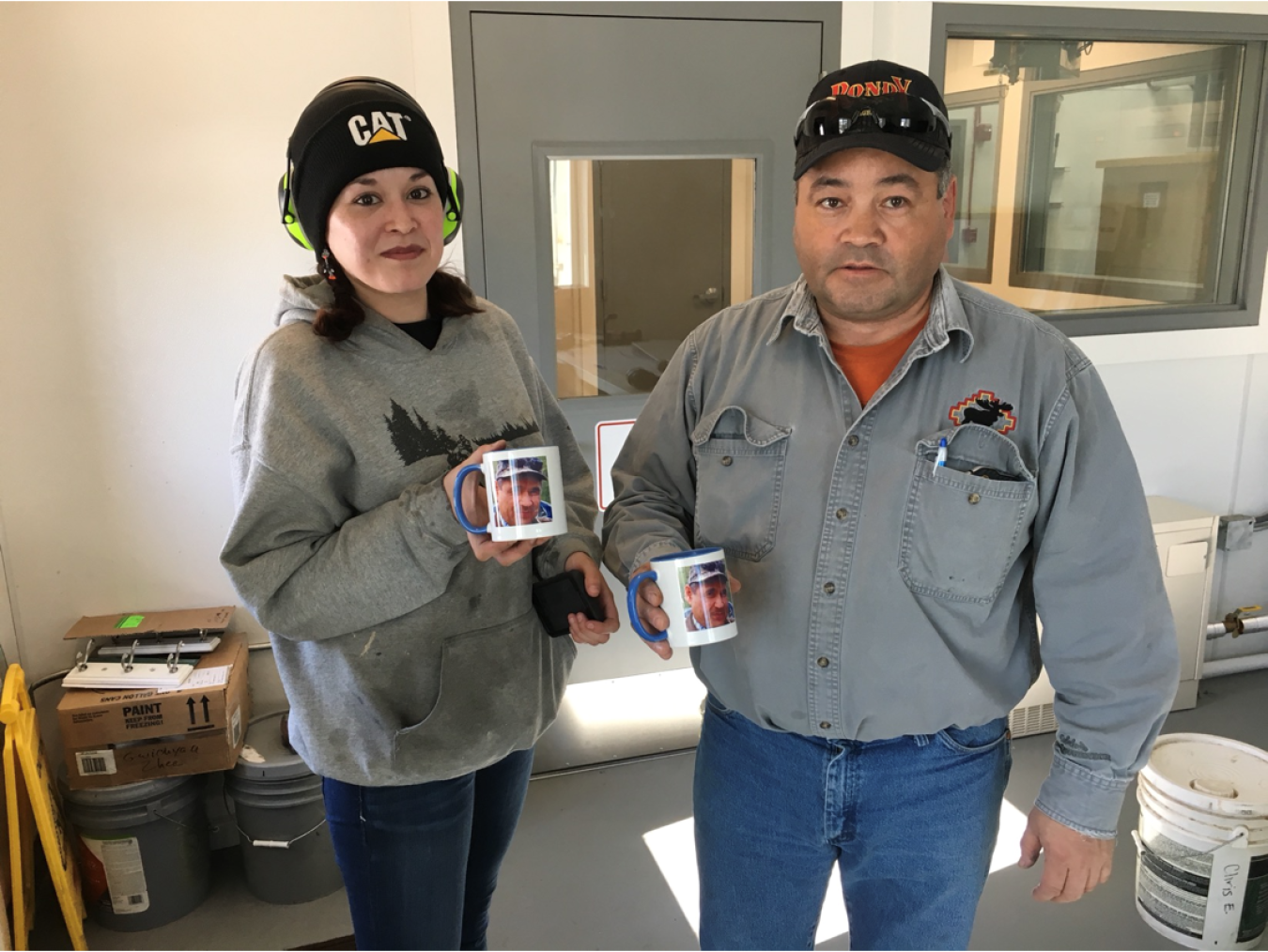 Two workers hold coffee cups in a utility facility.