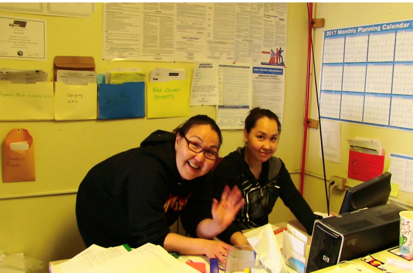 Rural utility staff at a computer monitor inside an office.