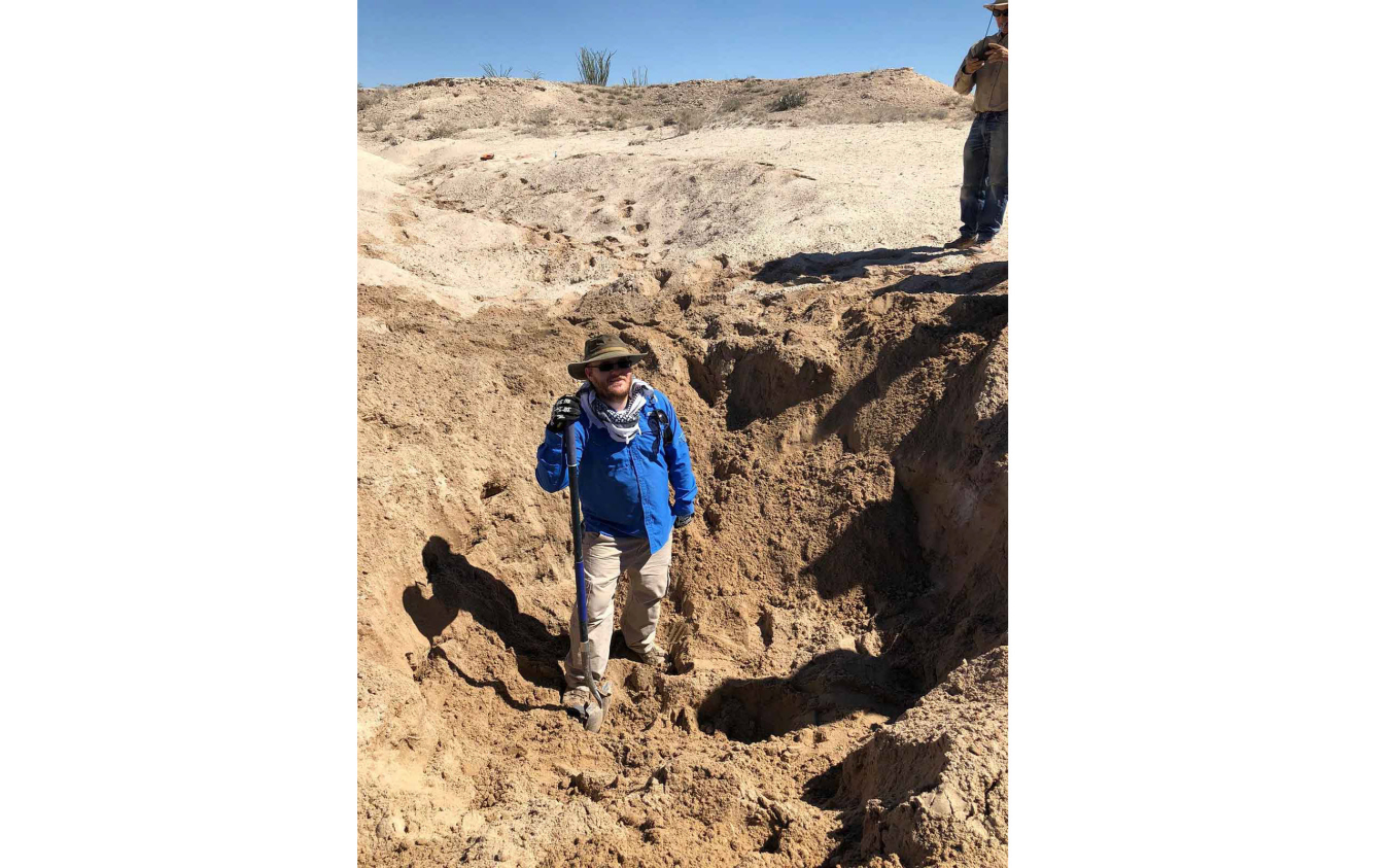 Alex Eddy standing in a sand pit holding a shovel