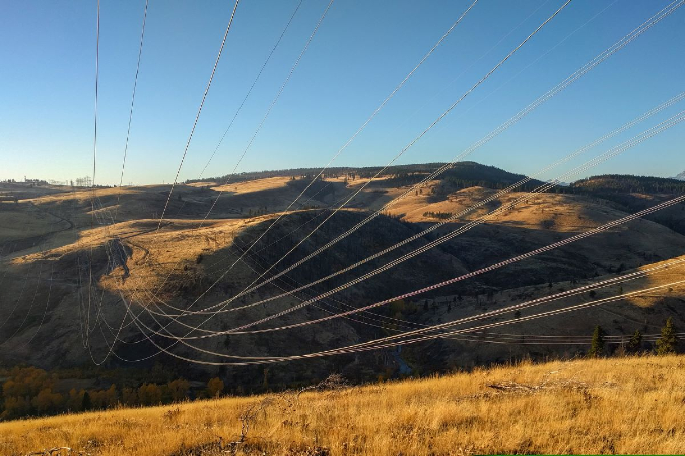 powerlines hang over a canyon with a clear sky above