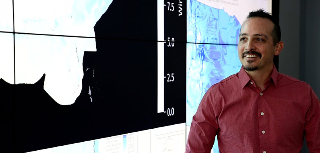 Anthony Lopez smiles in front of a graph backdrop.