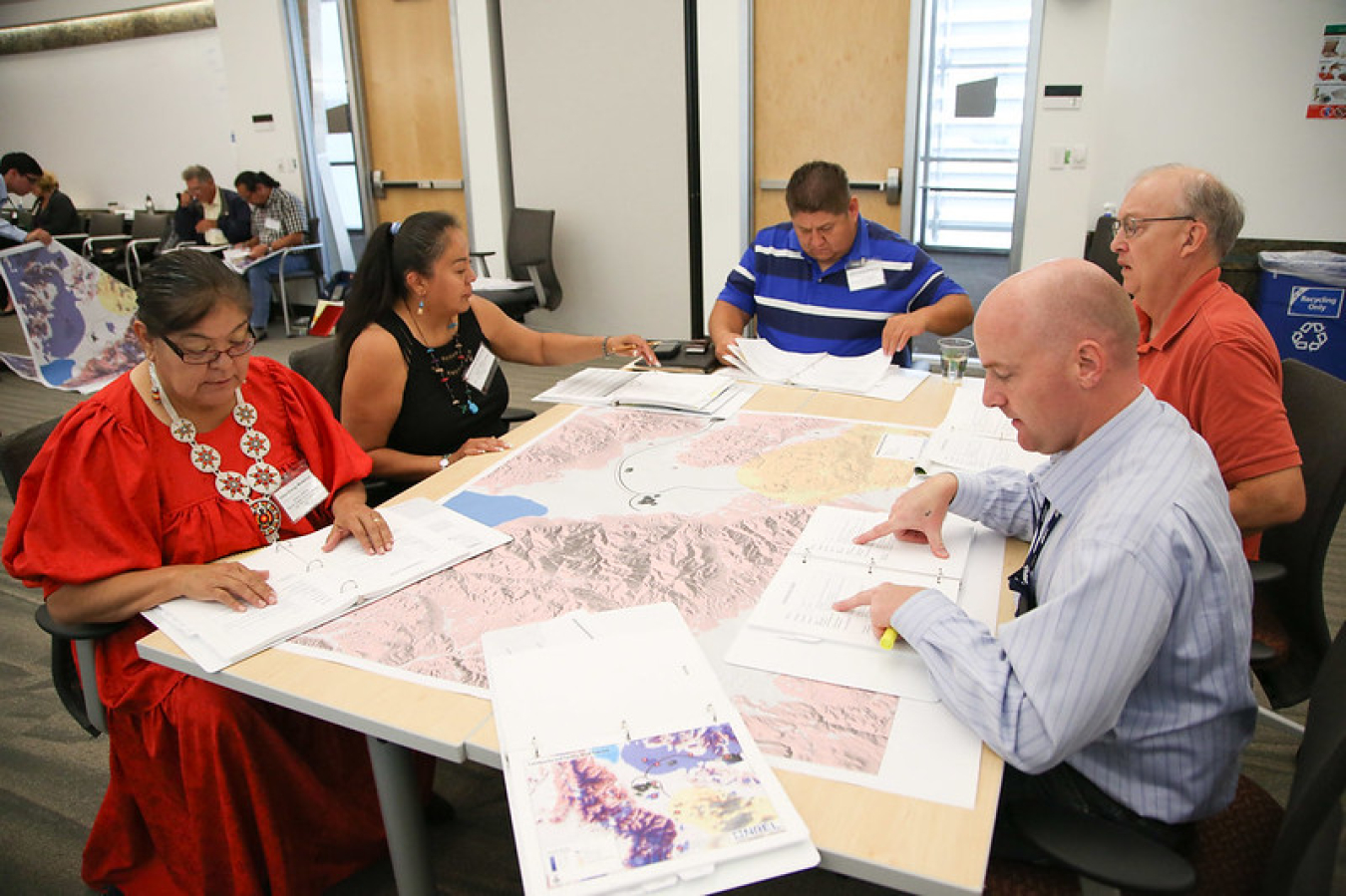 Five workshop participants sit around a large map.