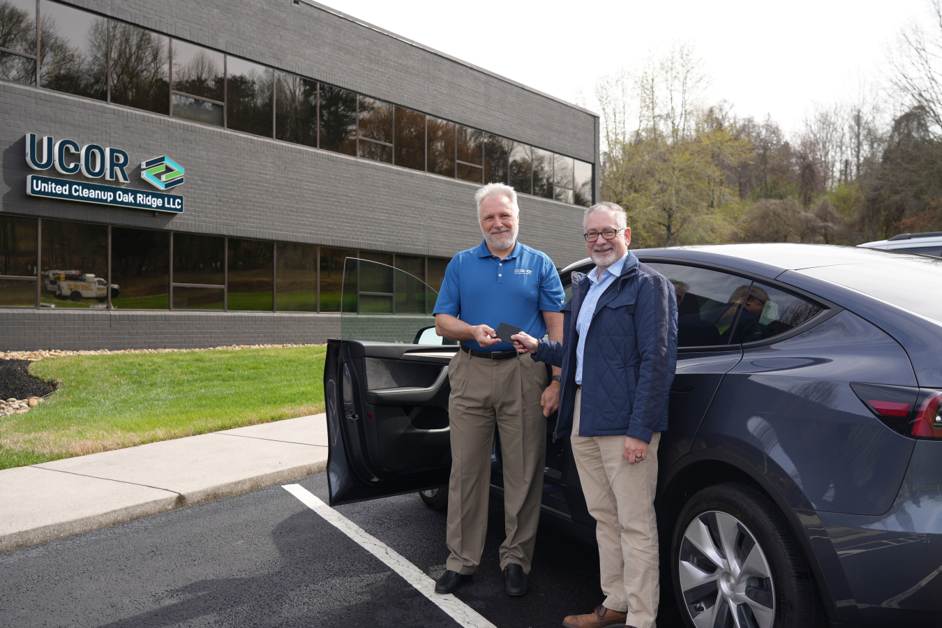 UCOR President and CEO Ken Rueter, left, and Oak Ridge Office of Environmental Management (OREM) Manager Jay Mullis hold a key card to the first electric vehicle that arrived in Oak Ridge. UCOR is set to receive 10 more electric vehicles as it begins transitioning its fleet. 
