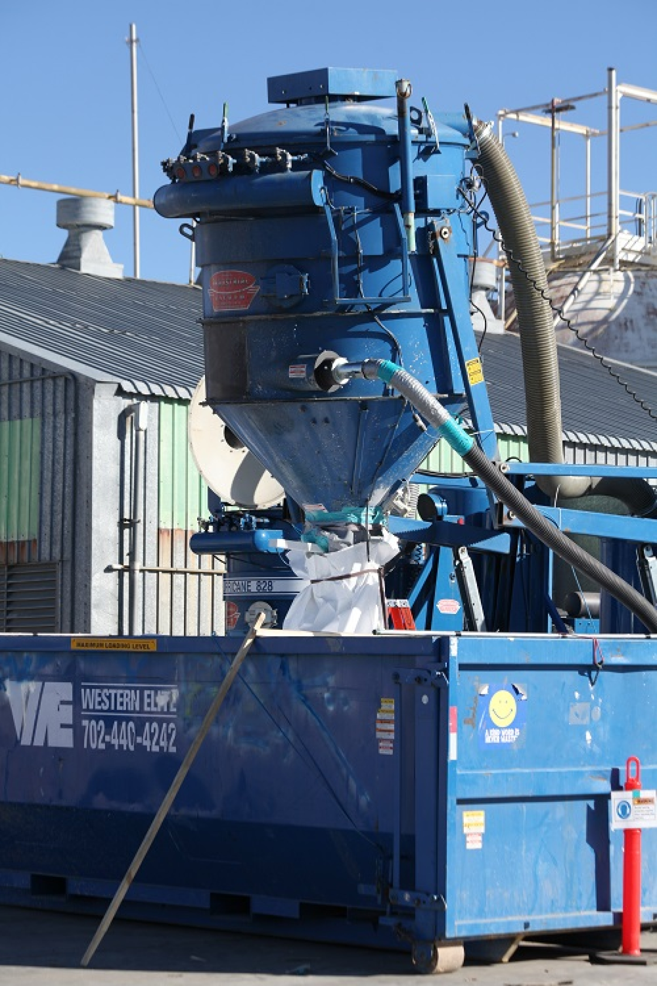 Perlite is vacuumed into a containment bag inside a roll-off canister.