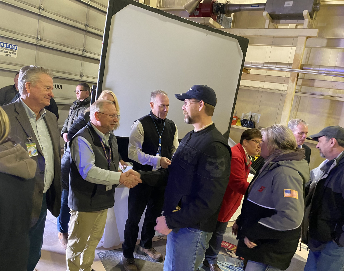 Idaho Gov. Brad Little, far left, and other officials shake hands with members of the workforce, thanking them for their hard work and help meeting a major cleanup milestone.