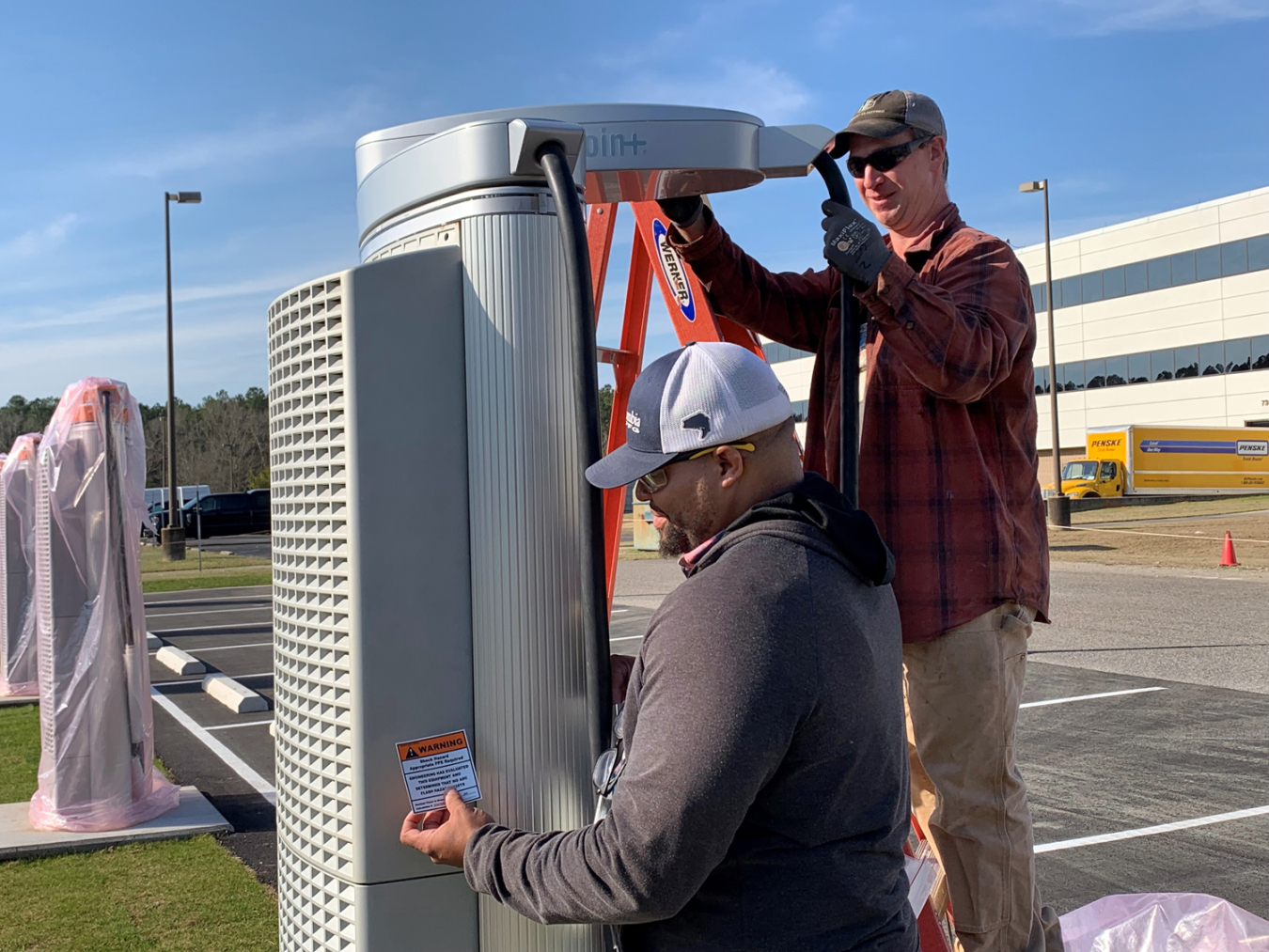 Savannah River Nuclear Solutions employee Alfonzo Thomas, left, helps Hebbard Electric electrician Greg Jamison prepare eight vehicle charging stations behind a building in the Savannah River Site’s B Area.