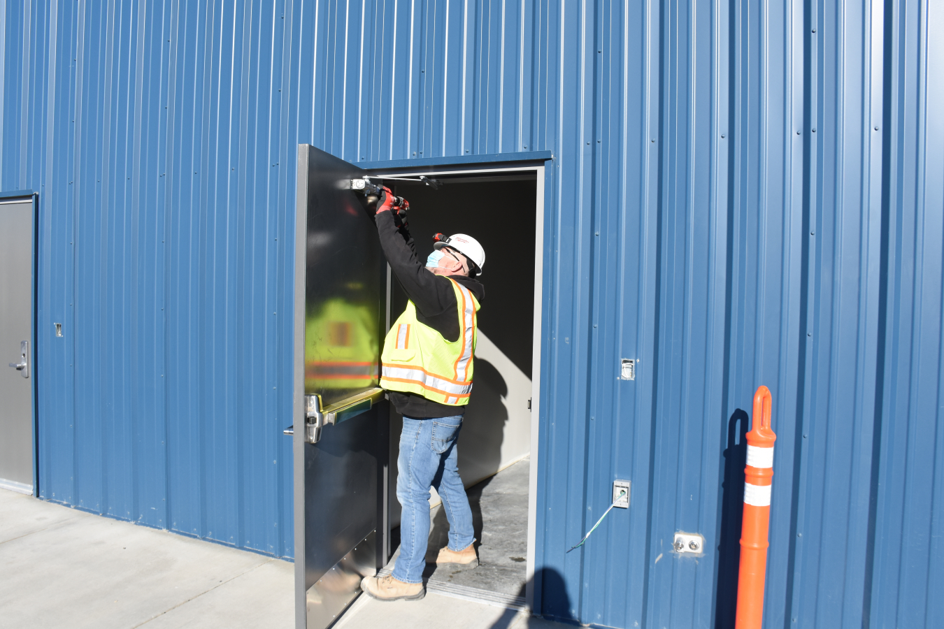 An employee from Fowler General Construction installs a hydraulic closer on a door at a new workshop the company built for craft workers supporting the tank waste storage and treatment mission at the Hanford Site.