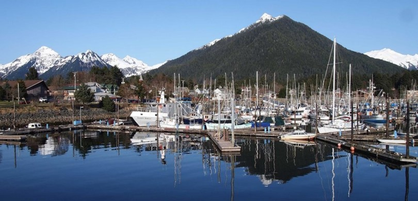 Boats at a dock with a snowy mountain in the background.