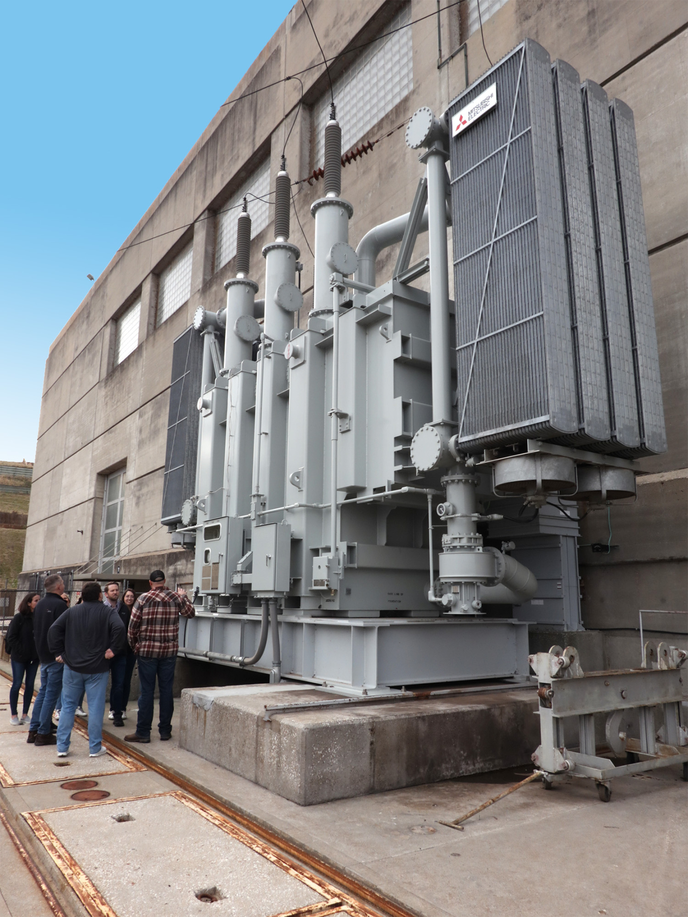 group of people touring dam and viewing a transformer