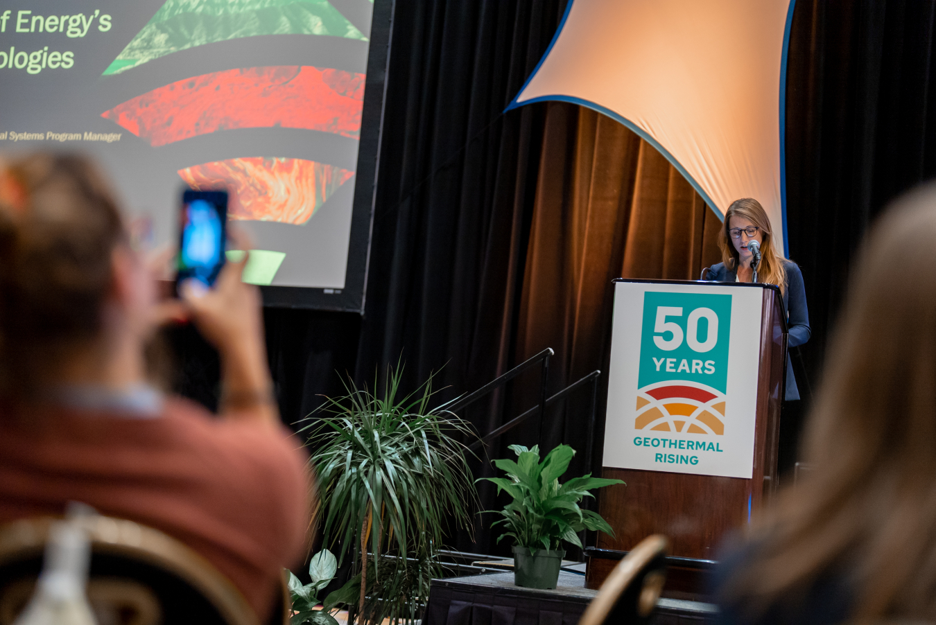 Lauren Boyd stars behind podium on stage presenting at the Geothermal Rising conference