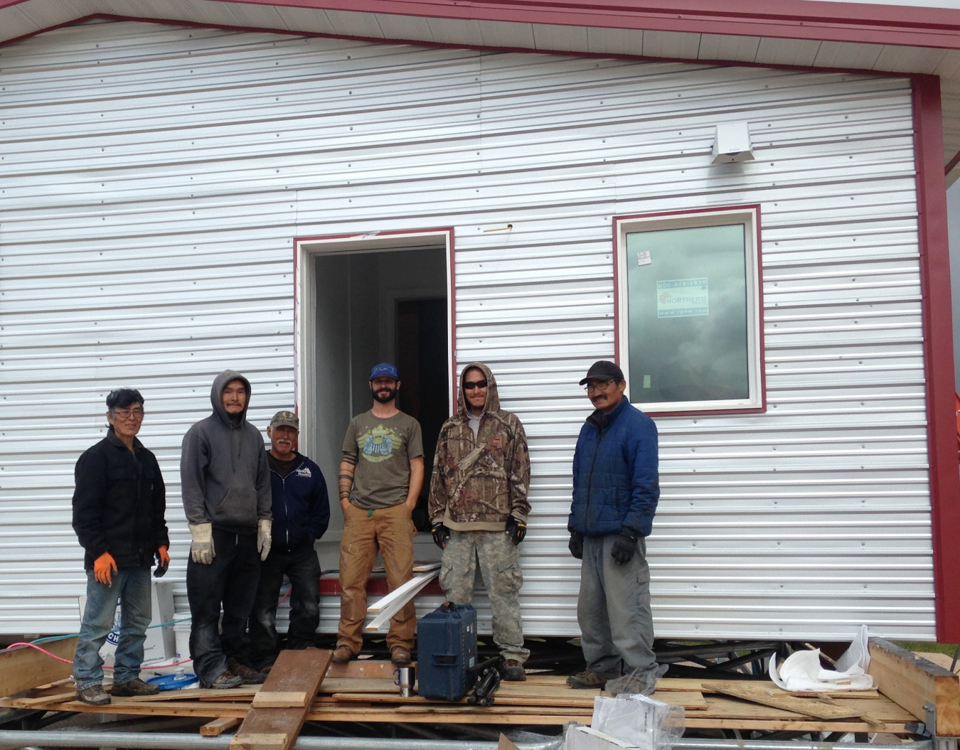 CCHRC staff stand with a local crew building a demonstration home in Mertarvik, Alaska. 