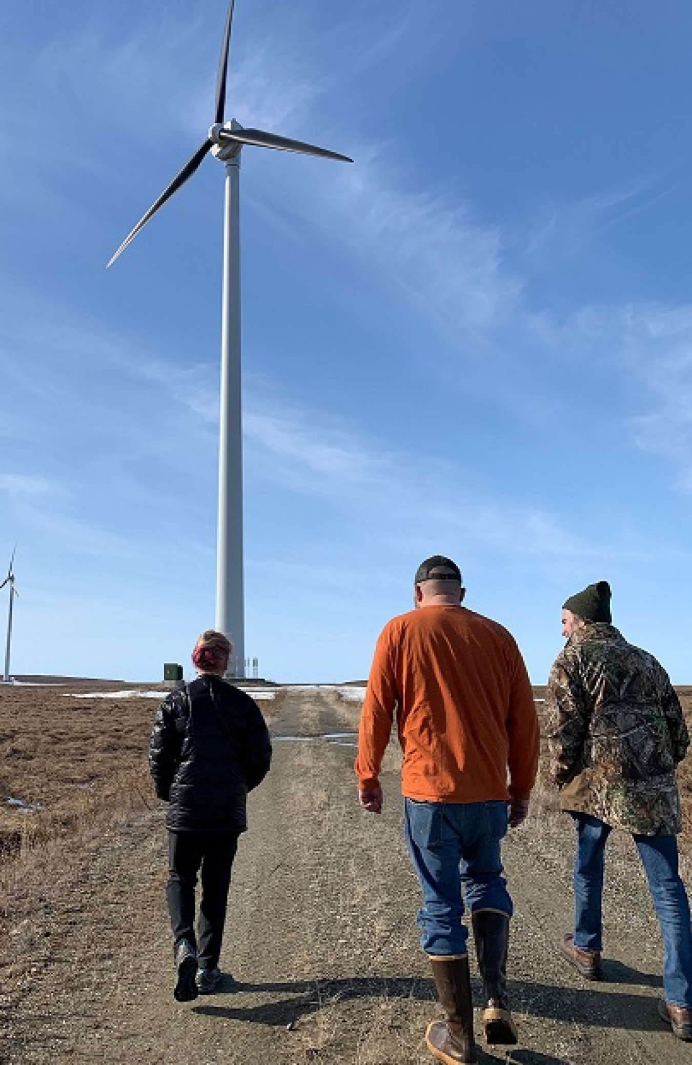 Arctic Energy Office team members walk with Dr. Richmond to a wind turbine in Kotzebue, Alaska.