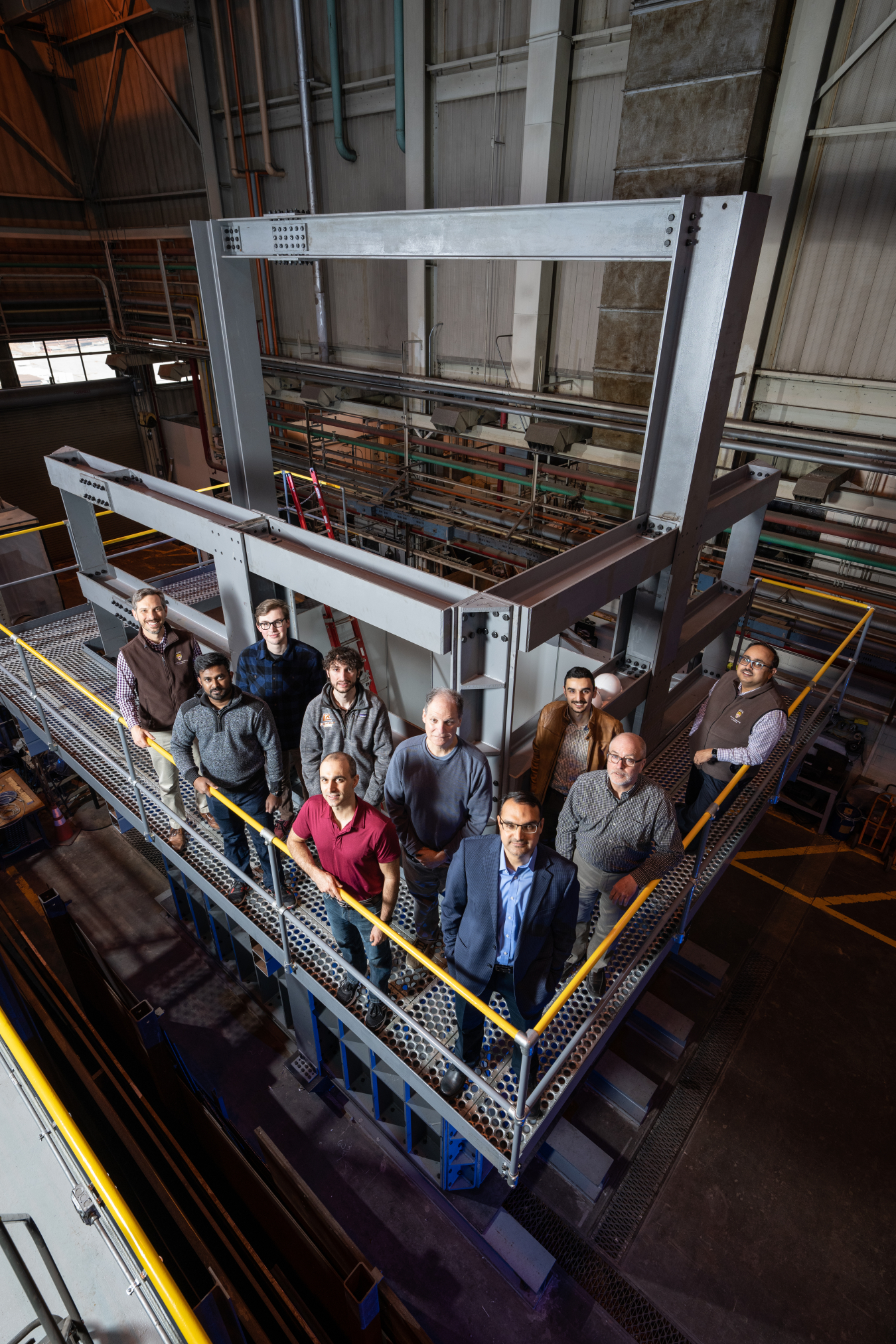 A group of people stand on a raised platform within a laboratory.