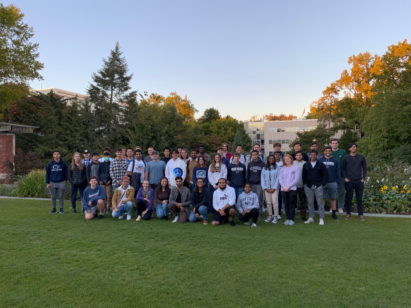 Three rows of students standing or kneeling on a lawn.