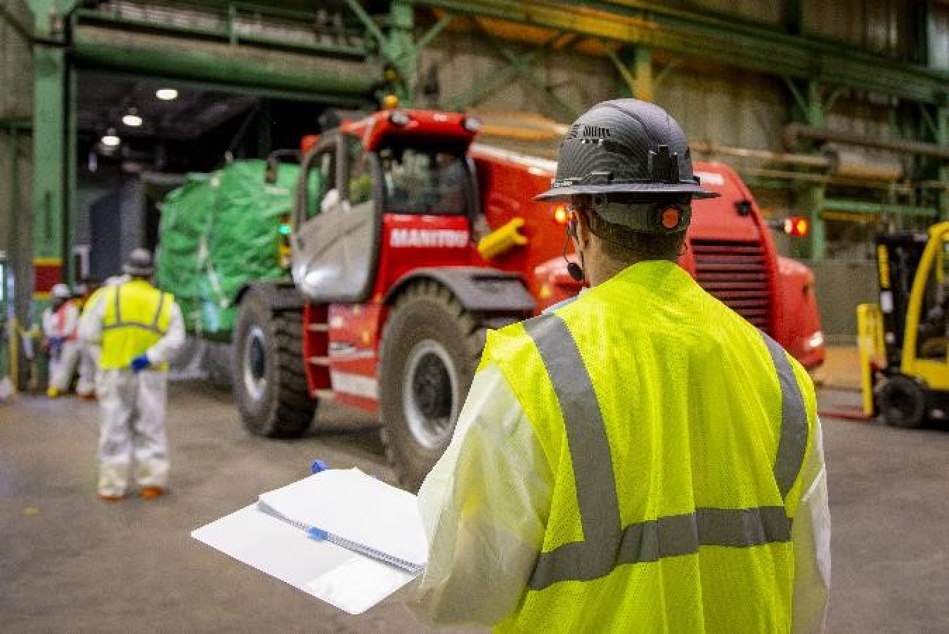 Workers load a compacted bundle into a specially designed storage container for storage onsite.
