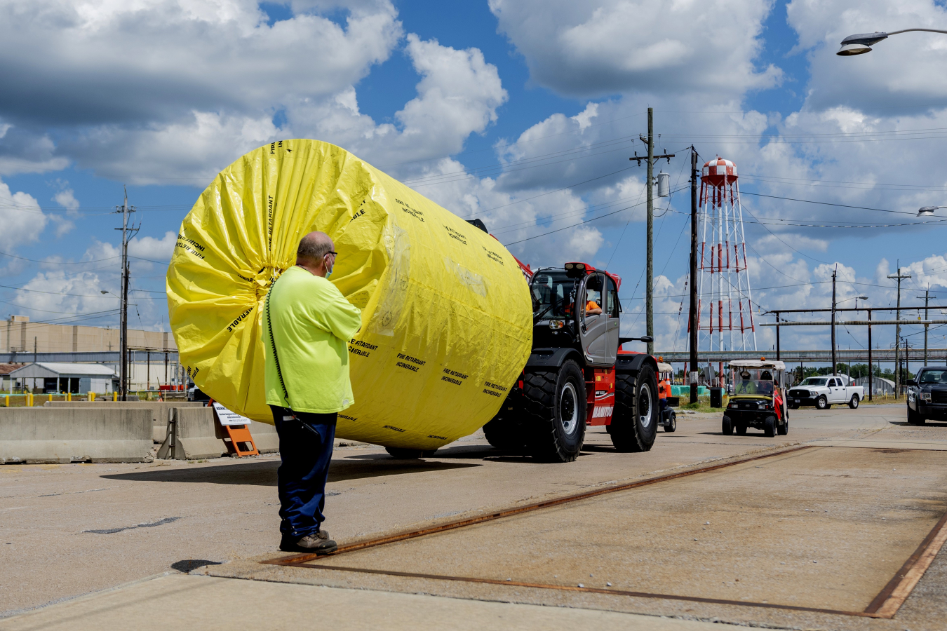 Deactivation Maintenance Mechanic Tommy Gorline works as a spotter for a telehandler transporting a surrogate bundle from the C-333 Process Building to the bundle compaction area. Surrogates were used to simulate the size and makeup of an actual converter bundle.