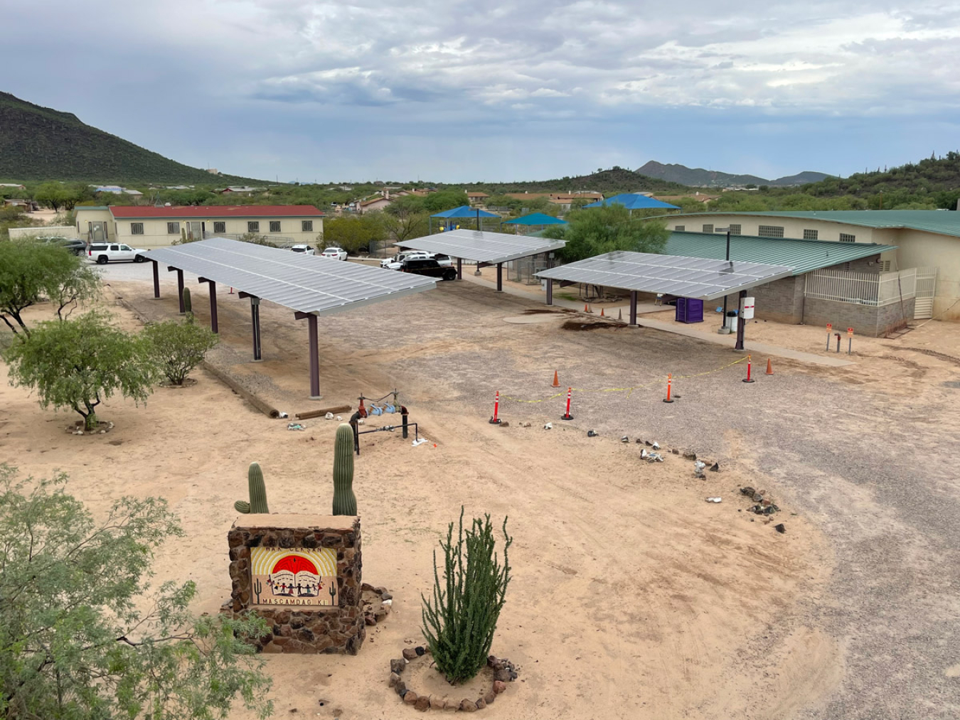 Three solar panels over a parking lot in a desert environment.