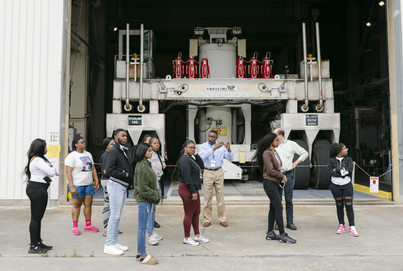 During a tour of the Savannah River Site for Claflin University students, Les Patten, at center, with EM liquid waste contractor Savannah River Mission Completion, describes a special vehicle used to safely transfer large stainless-steel canisters filled with vitrified, high-activity waste from the Defense Waste Processing Facility to a nearby structure for long-term storage.