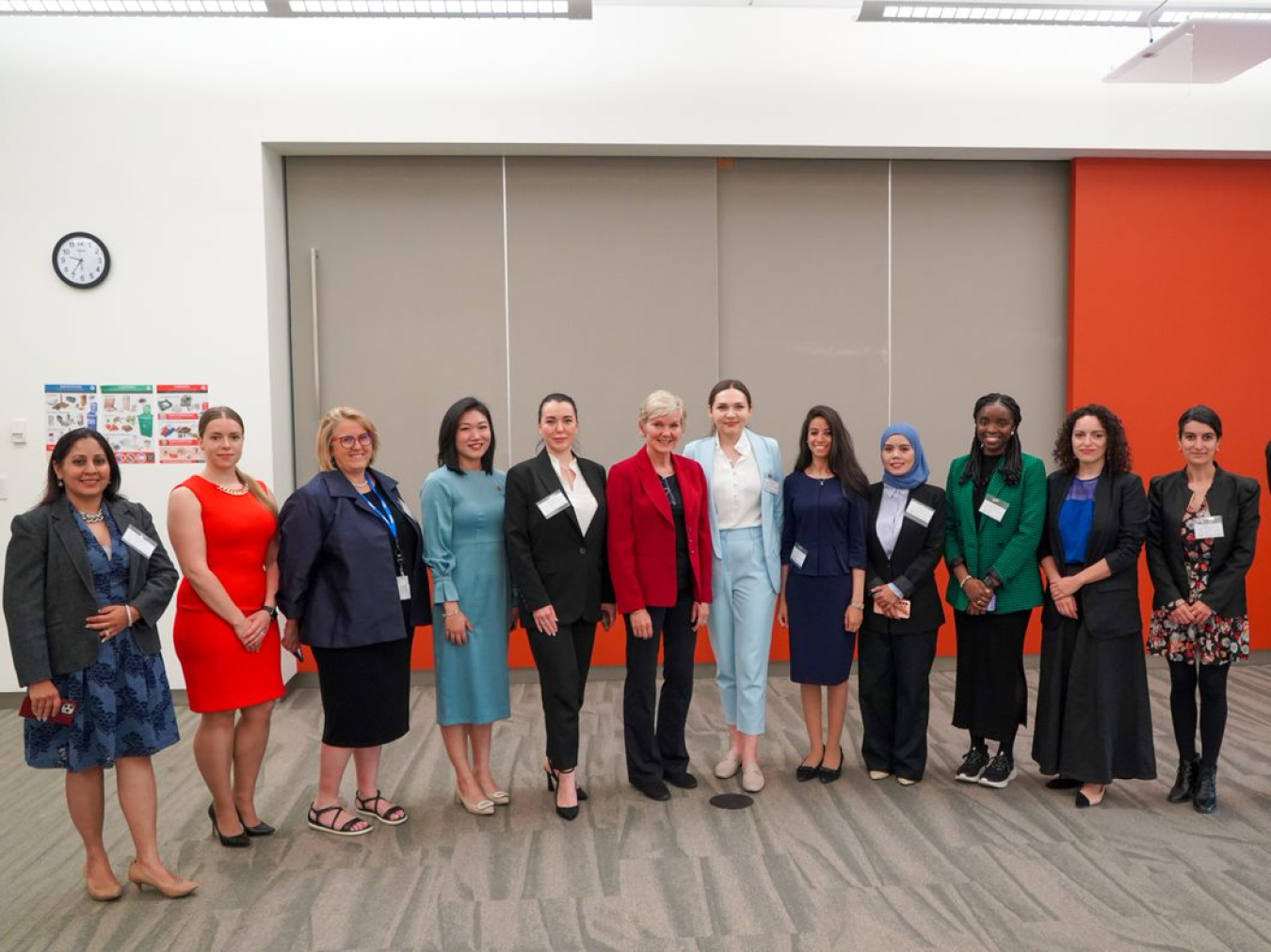 A group of women from Net Zero World countries and the Department of Energy pose for a photo in a meeting room.