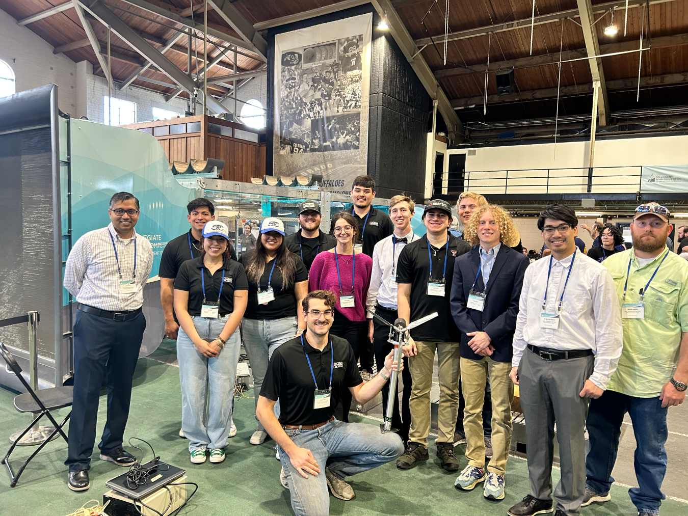 Team members of the Texas Tech collegiate wind competition stand around model wind turbines.