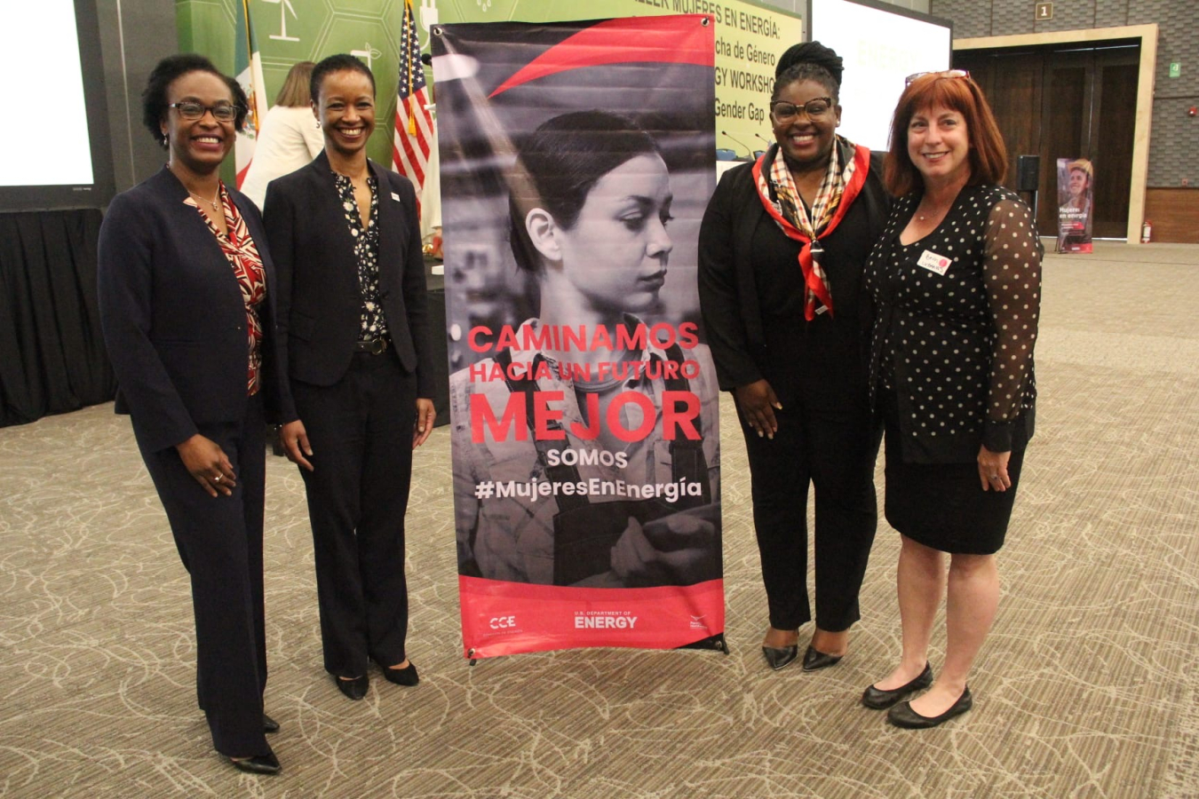 Office of International Affairs representatives pose for a photo with a USTDA representative and the U.S. Counsel General of Merida, Mexico next to an event sign in a conference venue for the Women in Energy event in Mexico.