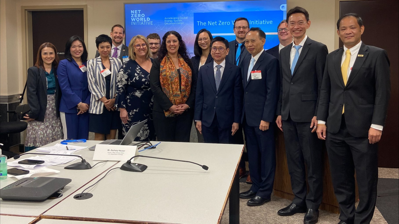 Department of Energy officials and the Thailand delegation pose for a photo in front of a computer screen in a conference room.