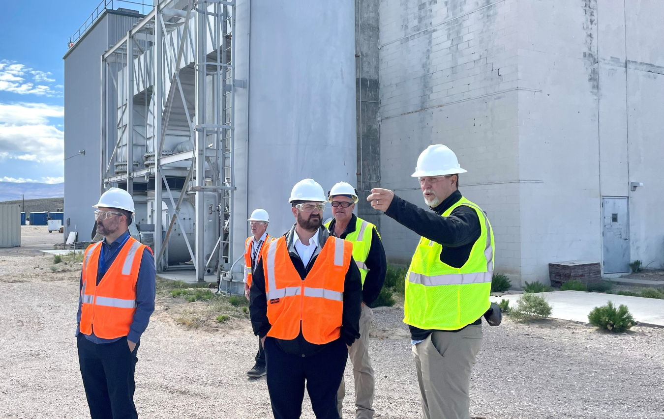 With the Engine, Maintenance, Assembly, and Disassembly Facility in the background, EM Nevada Program Manager Robert Boehlecke points to Test Cell C being staged for demolition while talking with EM Principal Deputy Assistant Secretary Jeff Avery.