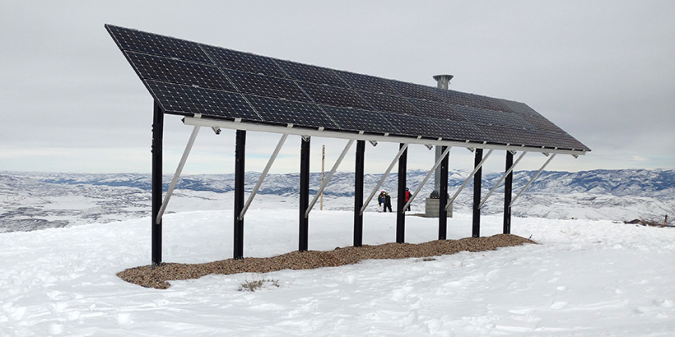 A solar array in the mountains surrounded by snow.