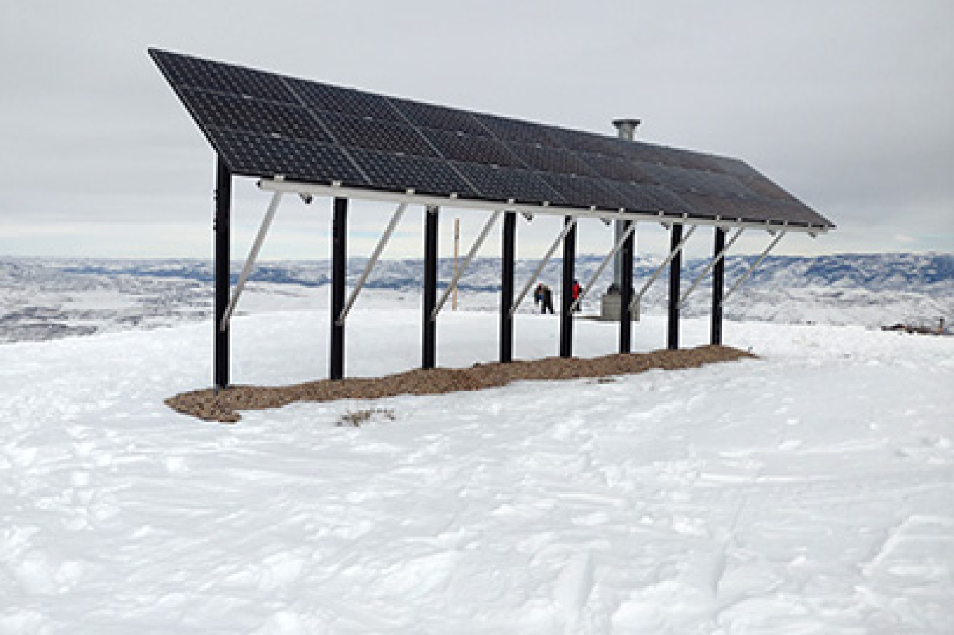 A solar array in the mountains surrounded by snow.
