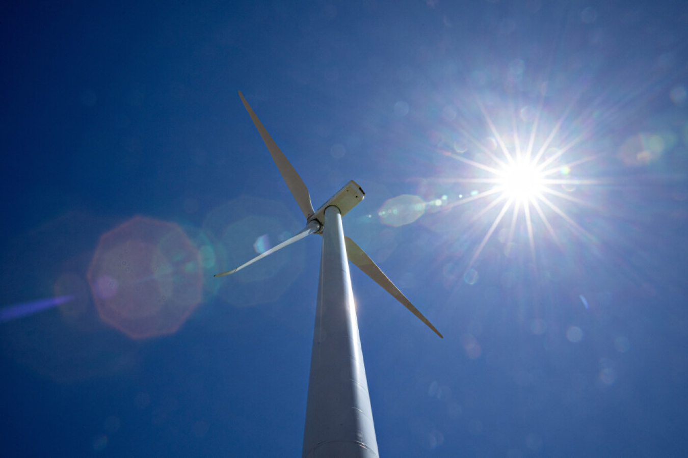 The sun shines down on a wind turbine.