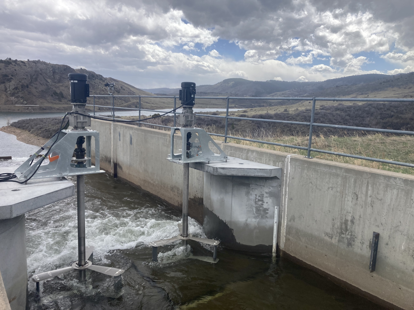 Two turbines spinning as water flows through a cement canal