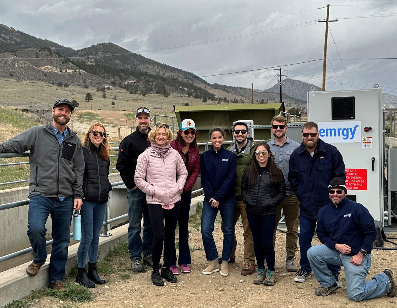 A group of people standing in front of a cement canal with hills in the background