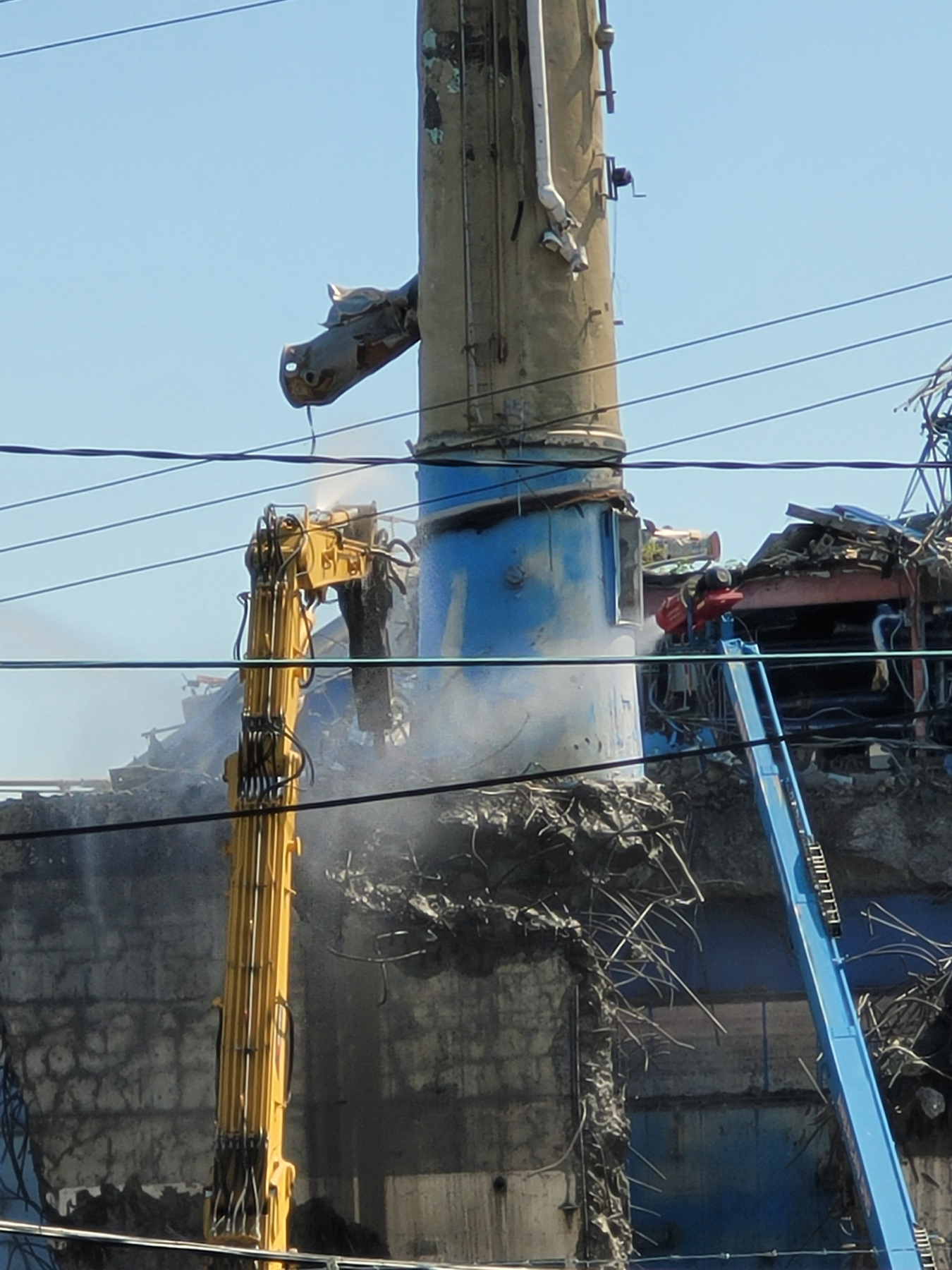 With the help of heavy equipment, an operator safely chipped away at the ventilation stack base before it came down in a pre-planned direction for its controlled removal.