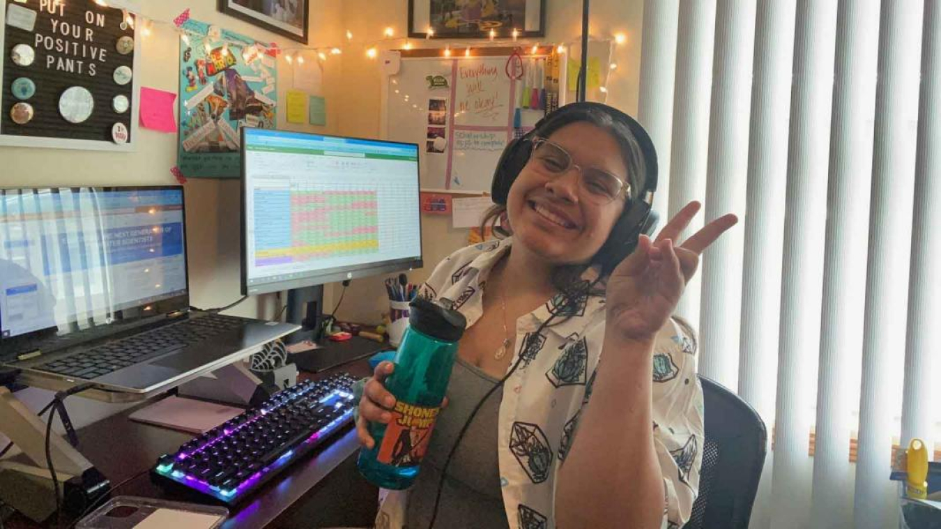 Guadalupe Medina sitting at her home office holding up her hand in a peace sign