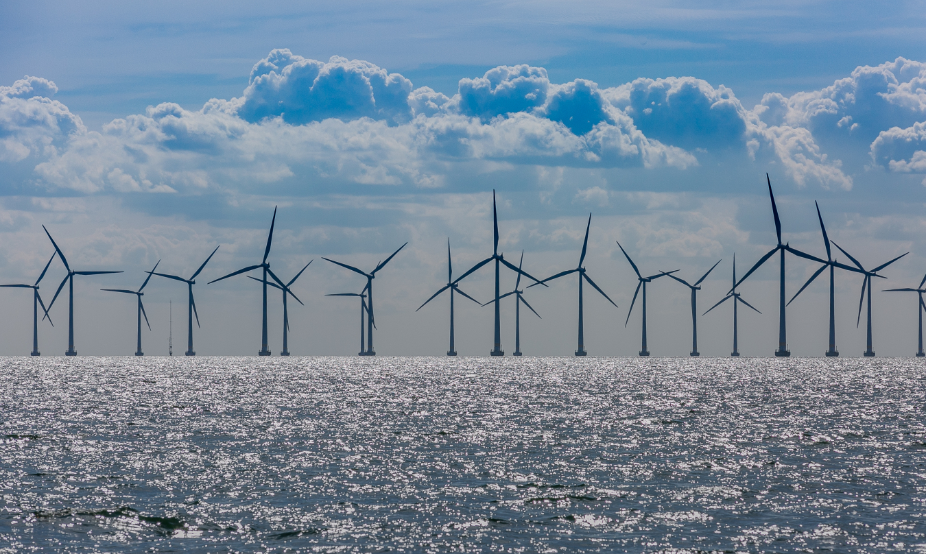 Offshore wind turbines against the sunset and clouds.