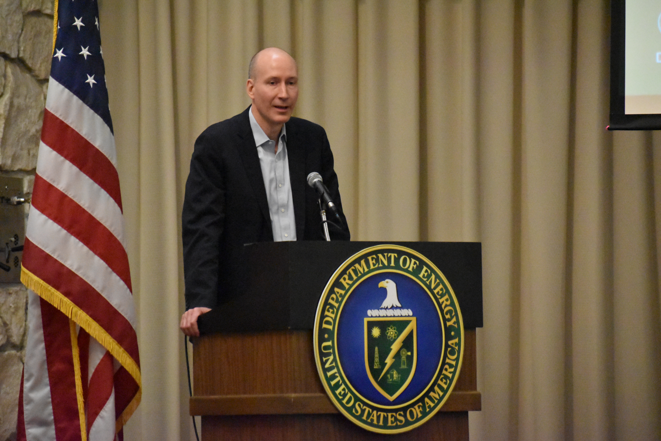 Speaker at podium with DOE seal and US Flag