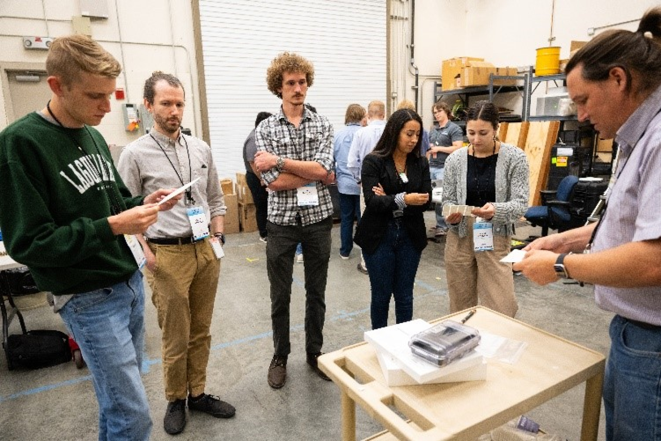 Young people stand around a table as an expert gives a technology demonstration.